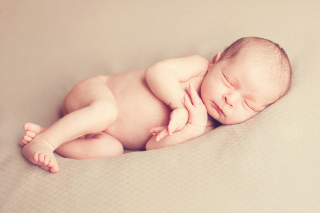 Newborn baby girl asleep on a blanket.